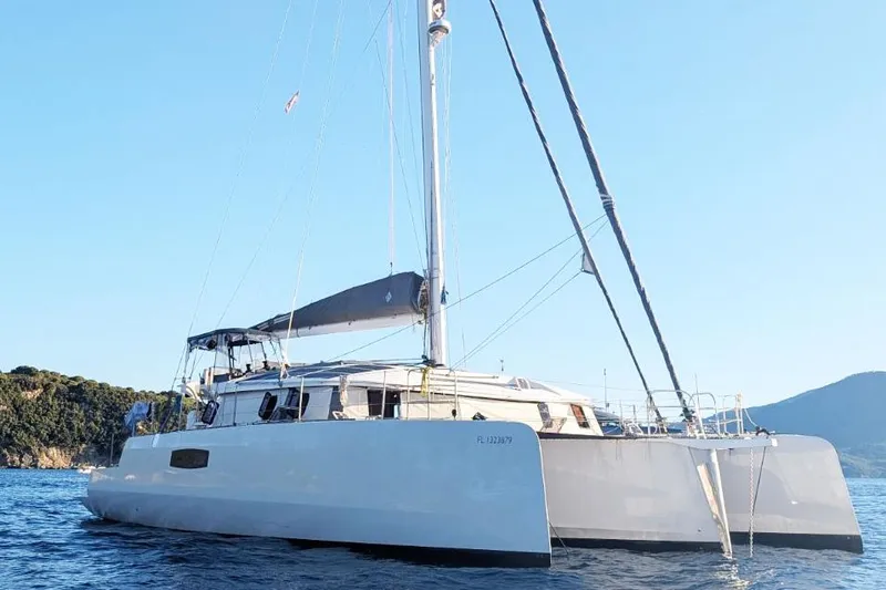 Dauntless Yacht Photos Pics 2022 NEEL 51 trimaran sailing on calm blue waters near a scenic coastline.