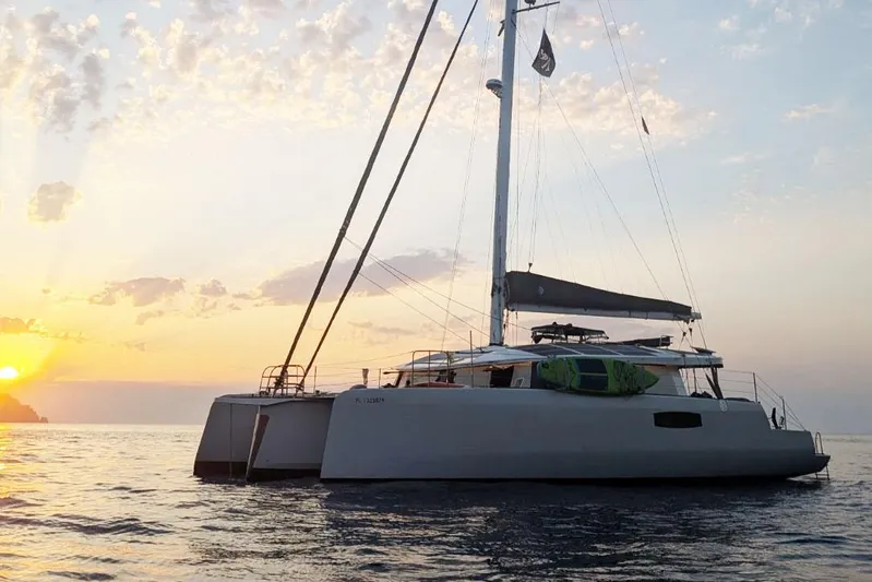 Dauntless Yacht Photos Pics Sailing catamaran NEEL 51 at sunset, 2022 model, on calm ocean waters.