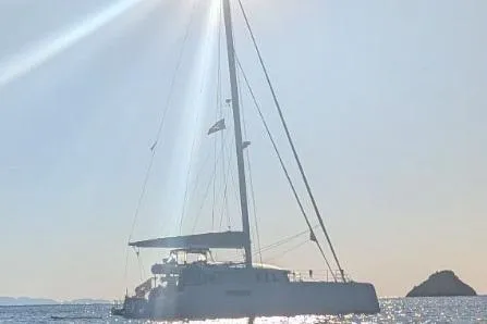 Dauntless Yacht Photos Pics Sailing yacht NEEL 51, 2022 model, gliding on sunlit sea near rocky island.