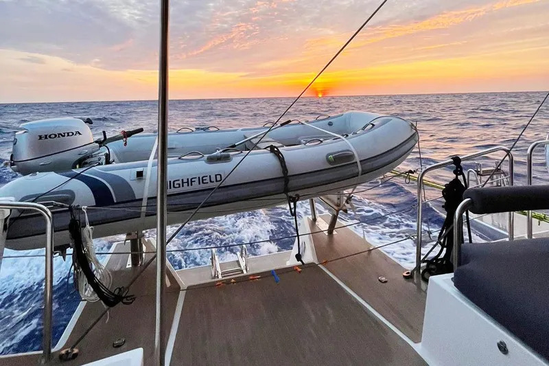 Dauntless Yacht Photos Pics Sailing at sunset on NEEL 51 trimaran, featuring a Highfield dinghy and Honda motor.