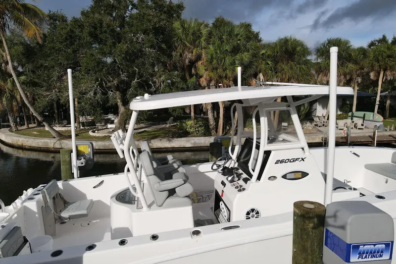  Yacht Photos Pics 2023 Twin Vee 260 GFX boat docked near lush greenery and calm waters.