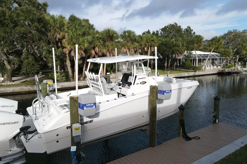  Yacht Photos Pics 2023 Twin Vee 260 GFX boat docked by a scenic canal with lush greenery.