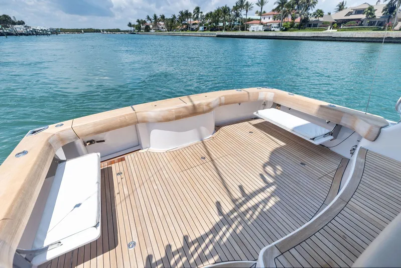 Milling Time Yacht Photos Pics 2016 Hatteras Express Sportfish boat deck with wooden flooring, overlooking serene waters.