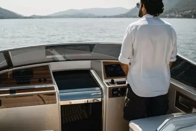 Man steering Ecoline Marine Ecolux 850 boat, 2022 model, on a scenic lake.