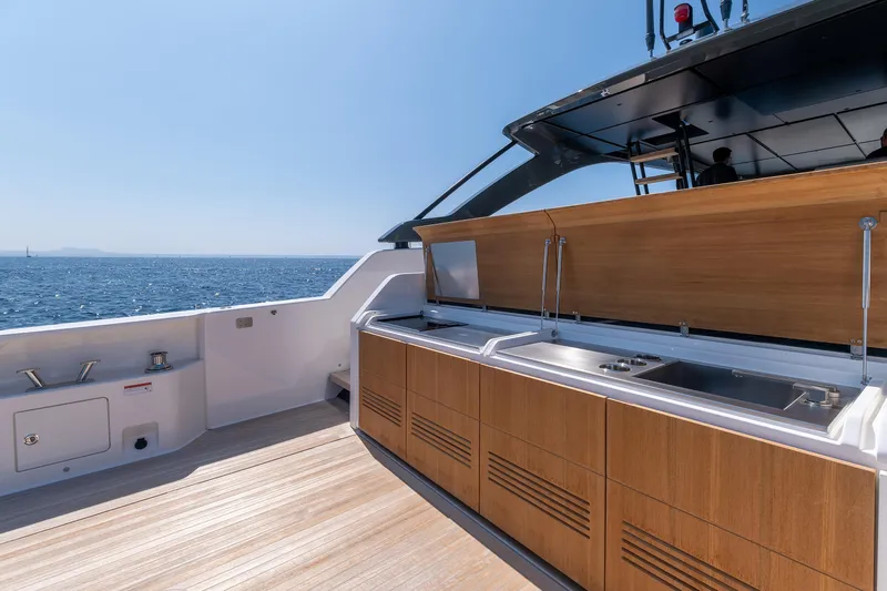  Yacht Photos Pics Luxurious outdoor kitchen on 2024 Bluegame 54 yacht, featuring sleek wood cabinetry and ocean view.