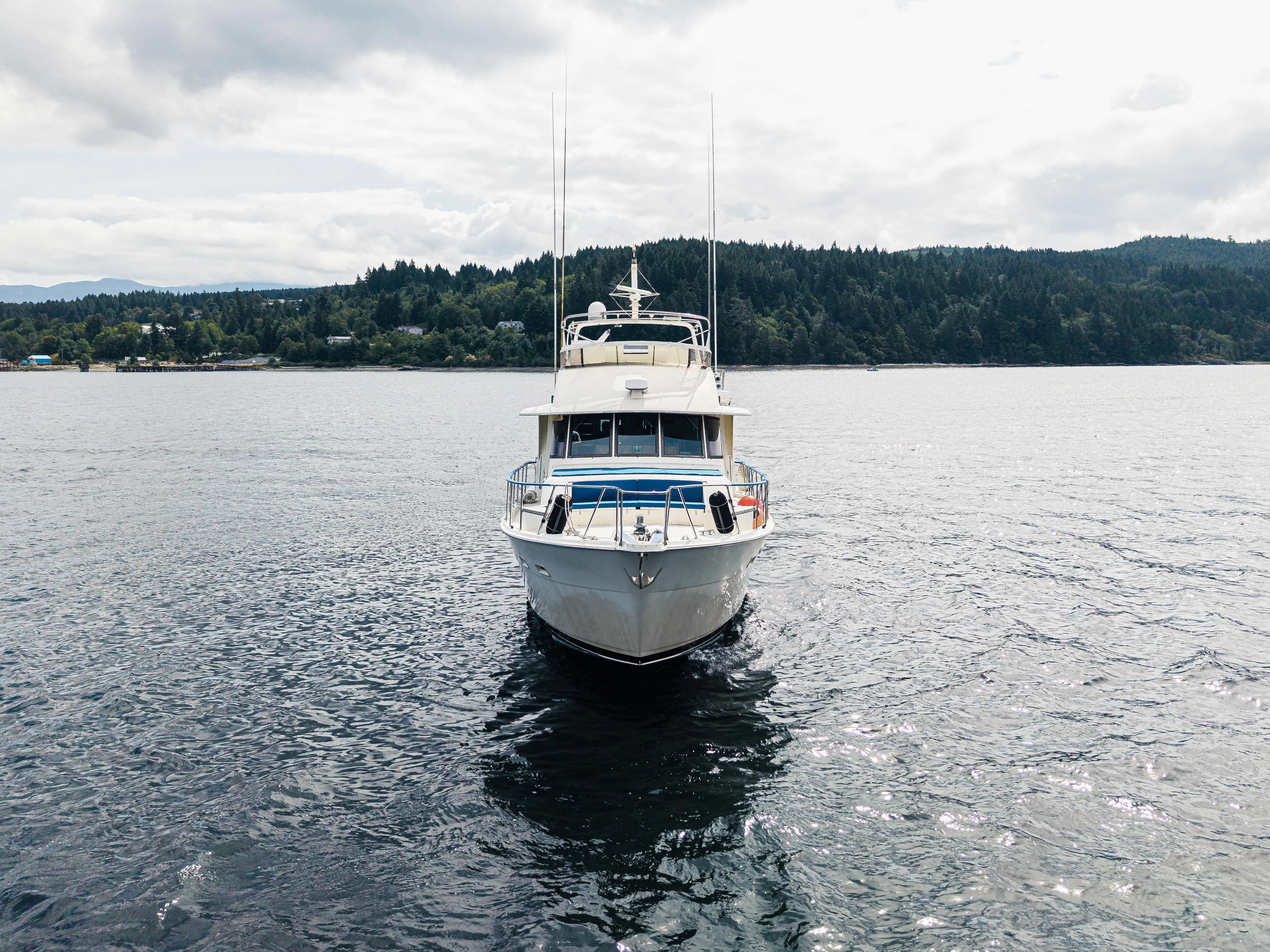  Yacht Photos Pics 1983 Hatteras Pleasure Craft on calm water with forested shoreline in background.