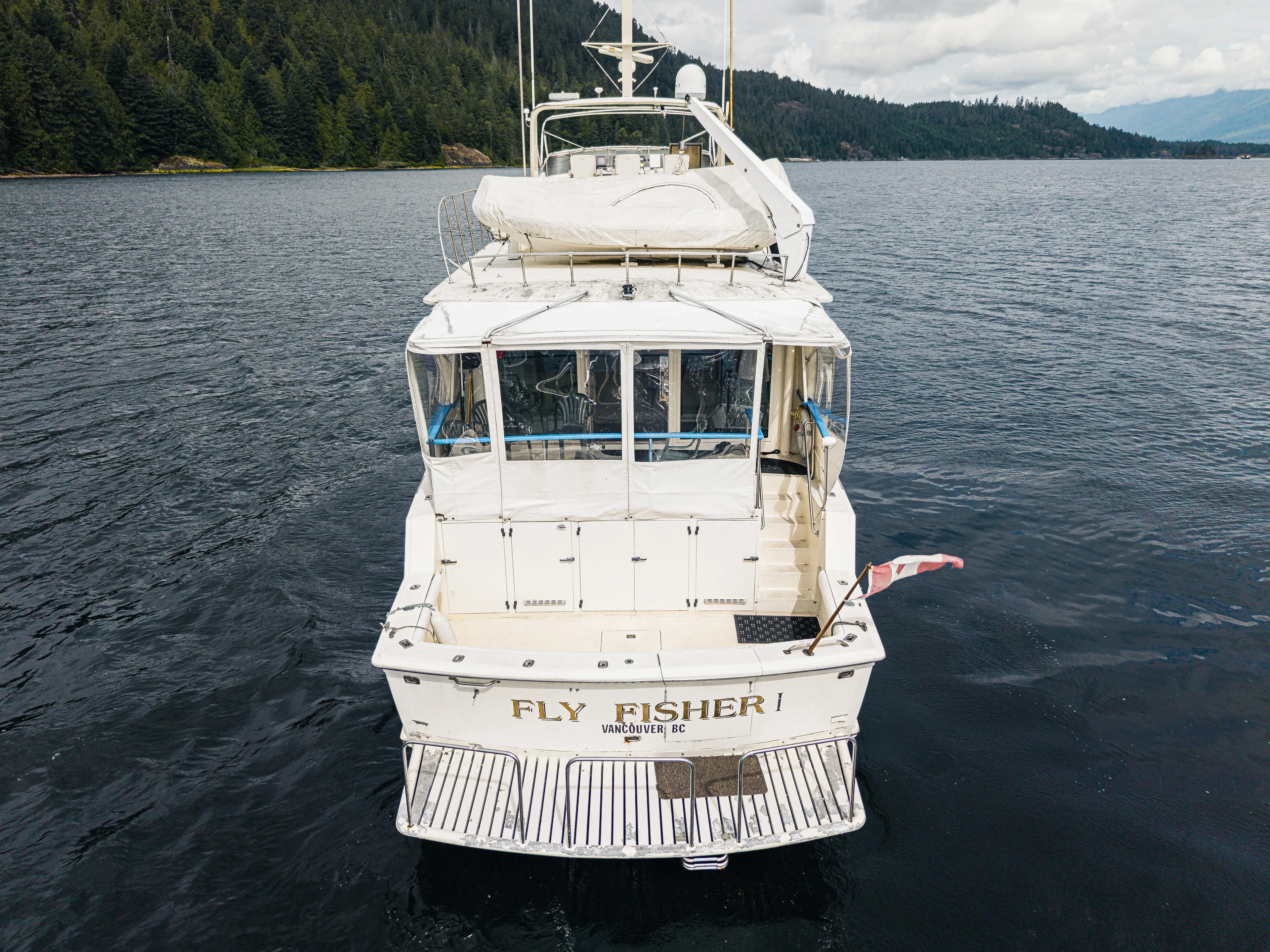  Yacht Photos Pics 1983 Hatteras Pleasure Craft on water, rear view, surrounded by forested landscape.