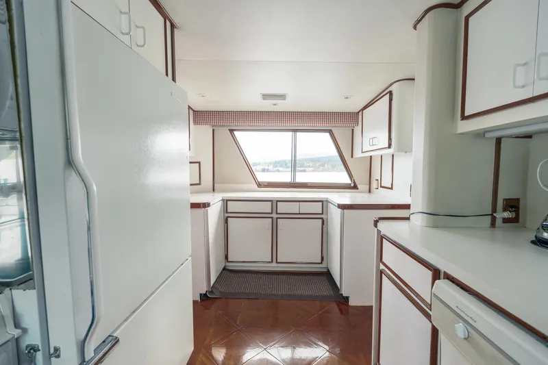  Yacht Photos Pics 1983 Hatteras Pleasure Craft kitchen with white cabinetry and large window view.