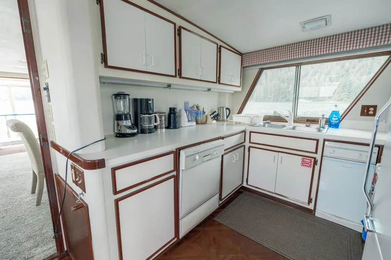  Yacht Photos Pics 1983 Hatteras Pleasure Craft kitchen with white cabinets, appliances, and large window view.
