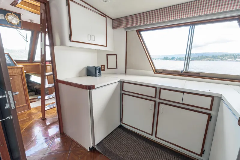  Yacht Photos Pics 1983 Hatteras Pleasure Craft interior with cabinets, window view, and wooden flooring.