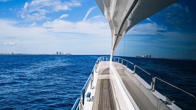 Golden Ours Yacht Photos Pics 2019 Sunseeker Motoryacht cruising on open blue sea with city skyline in distance.