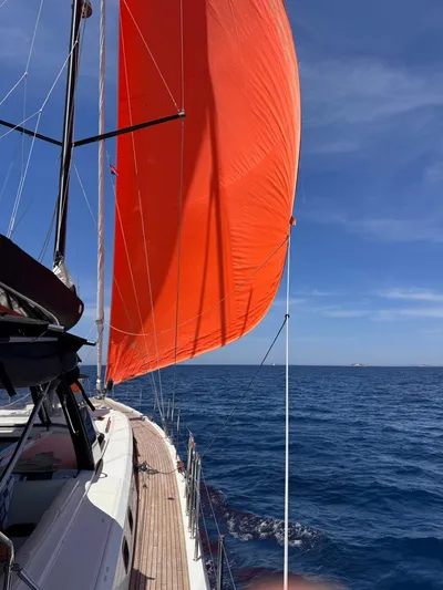 Manona (name Reserved For Owner) Yacht Photos Pics Beneteau Oceanis Yacht 62 (2018) sailing with vibrant orange sail on open sea.