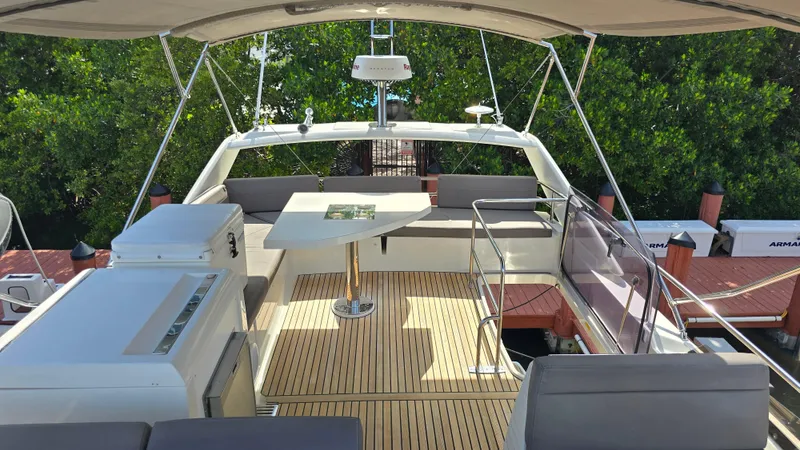  Yacht Photos Pics Luxurious 2018 Prestige 460 yacht deck with seating, table, and canopy, docked near lush greenery.