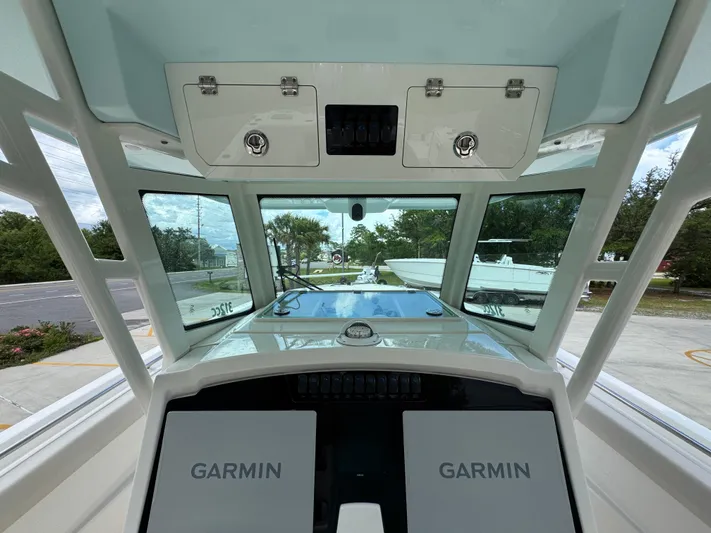  Yacht Photos Pics 2023 Sailfish 312 CC boat cockpit with Garmin navigation displays and overhead storage.