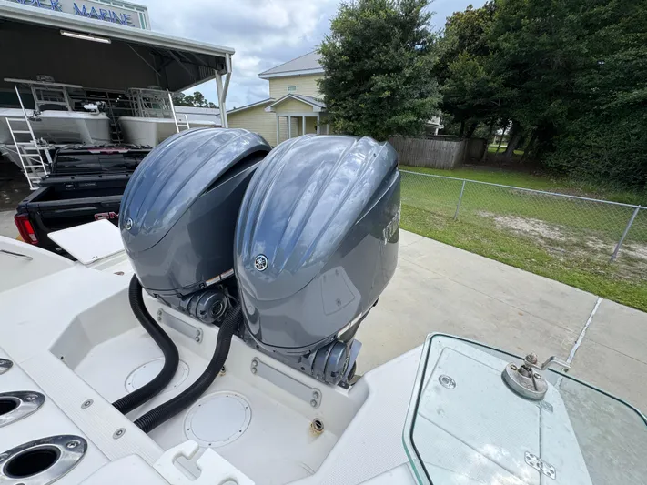 Yacht Photos Pics 2023 Sailfish 312 CC boat with dual outboard motors, parked near a marine facility.