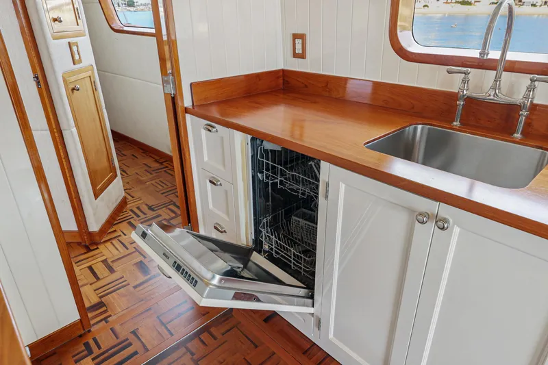 Amakua Yacht Photos Pics 1970 Hargrave Yachtfisher kitchen with open dishwasher, wooden countertops, and stainless steel sink.