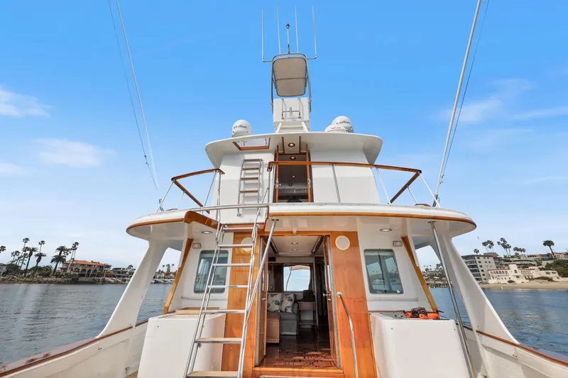 Amakua Yacht Photos Pics 1970 Hargrave Yachtfisher with wooden accents, docked near coastal homes under a clear blue sky.