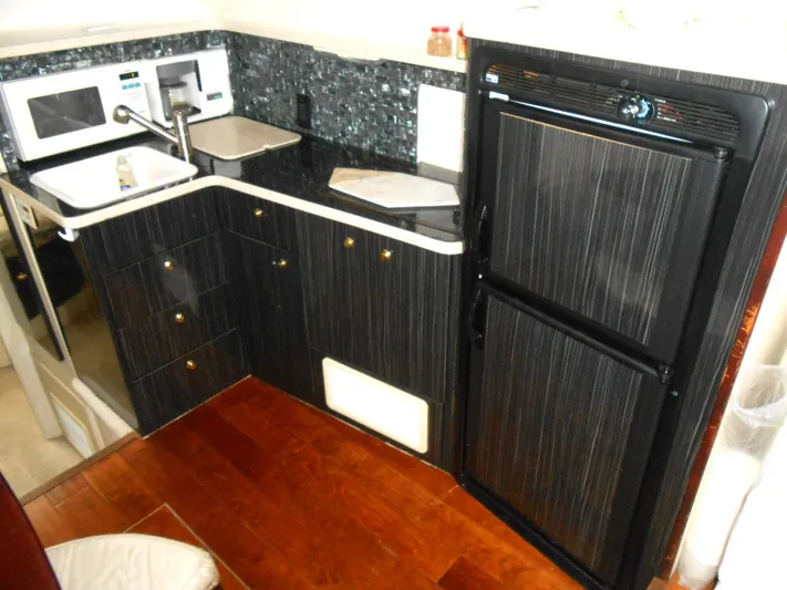 Fifty-150 Yacht Photos Pics 1999 Silverton 352 MY yacht kitchen with black cabinetry, microwave, sink, and refrigerator.