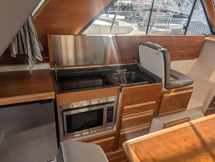  Yacht Photos Pics 2022 Cutwater C-32 CB yacht interior kitchen with microwave, sink, and seating.