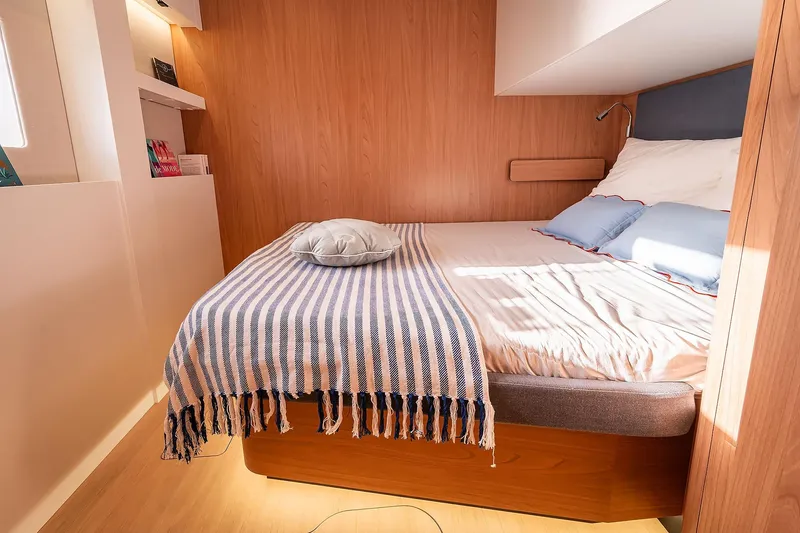 Voila Yacht Photos Pics Cozy bedroom in 2026 Bali 5.2 yacht with striped blanket and wooden accents.