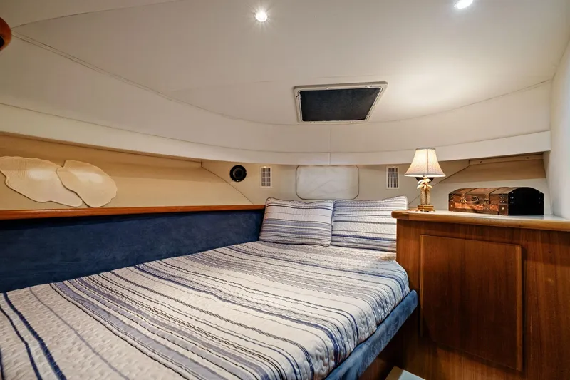 Starship Yacht Photos Pics 1996 Carver 440 Aft Cabin Motor Yacht bedroom with striped bedding and cozy lighting.