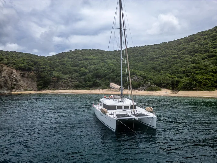 Cascadia 2 Yacht Photos Pics Lagoon 560 catamaran anchored near a lush, green island coastline, 2012 model.