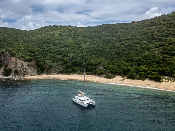 Cascadia 2 Yacht Photos Pics Lagoon 560 catamaran anchored near a secluded beach with lush green hills, 2012 model.