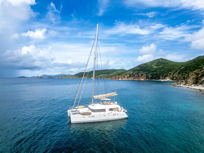 Cascadia 2 Yacht Photos Pics Lagoon 560 catamaran sailing near lush coastline under a vibrant blue sky, 2012 model.