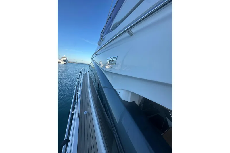  Yacht Photos Pics 2020 Princess S62 yacht side view on calm water under clear blue sky.