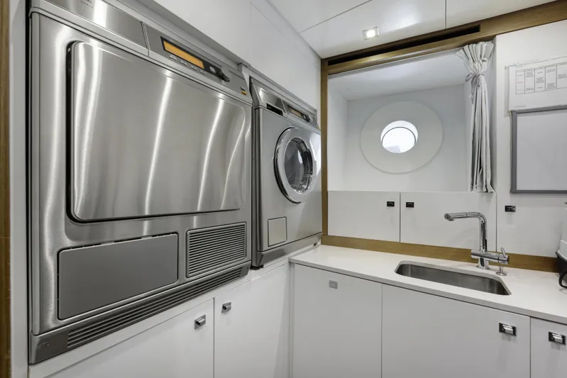 Serenity Yacht Photos Pics Laundry room on 2015 Mondomarine SF40 yacht with washer, dryer, and porthole window.