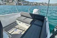 2022 Quarken 27 T-Top boat with seating, on calm water near a coastal town.