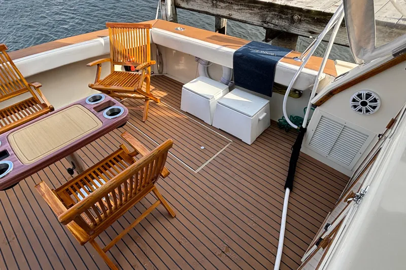  Yacht Photos Pics 1986 Viking 48 Convertible yacht deck with wooden chairs and table, docked by water.