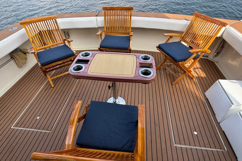  Yacht Photos Pics Deck of 1986 Viking 48 Convertible yacht with wooden chairs and table, overlooking water.