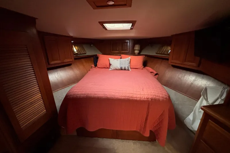  Yacht Photos Pics Cozy bedroom in 1986 Viking 48 Convertible yacht with red bedding and wooden cabinetry.