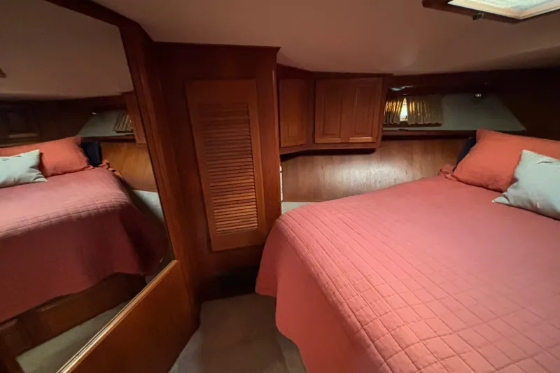  Yacht Photos Pics Cozy bedroom interior of 1986 Viking 48 Convertible yacht with red bedding and wooden cabinetry.