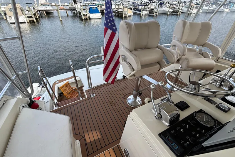  Yacht Photos Pics 1986 Viking 48 Convertible yacht helm with chairs, American flag, and marina view.