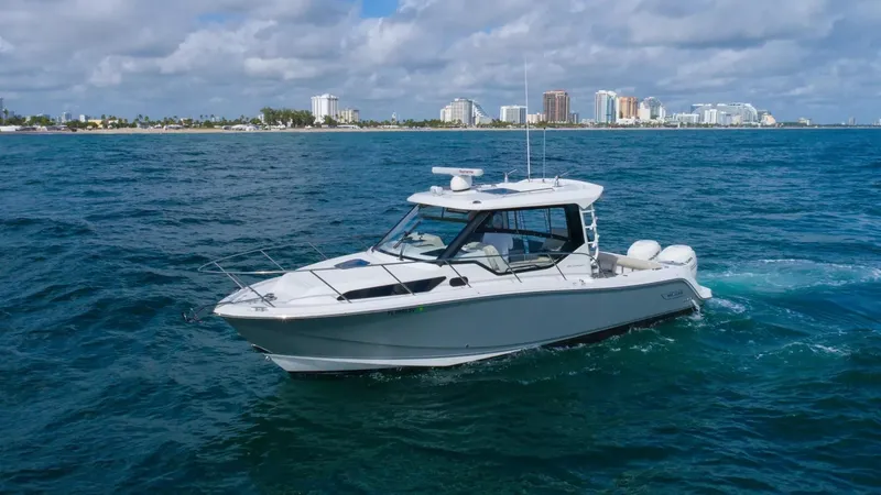  Yacht Photos Pics 2020 Boston Whaler 325 Conquest cruising on ocean with city skyline in background.