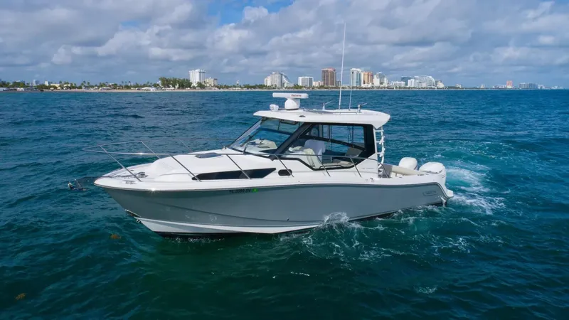  Yacht Photos Pics 2020 Boston Whaler 325 Conquest cruising on blue ocean near city skyline.