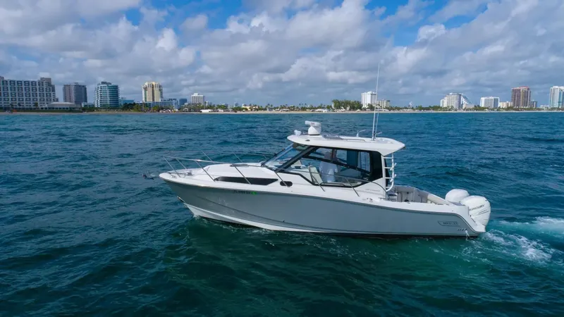  Yacht Photos Pics 2020 Boston Whaler 325 Conquest cruising on ocean near city skyline.