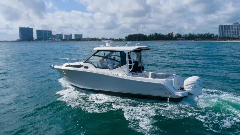  Yacht Photos Pics 2020 Boston Whaler 325 Conquest cruising on ocean near city skyline.