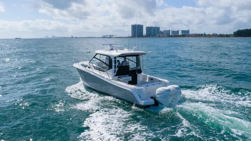  Yacht Photos Pics 2020 Boston Whaler 325 Conquest cruising on open water near a city skyline.