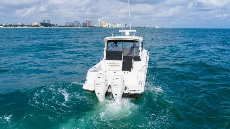  Yacht Photos Pics 2020 Boston Whaler 325 Conquest cruising on ocean with city skyline in background.