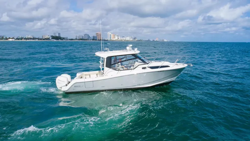  Yacht Photos Pics 2020 Boston Whaler 325 Conquest cruising on open ocean with city skyline in background.