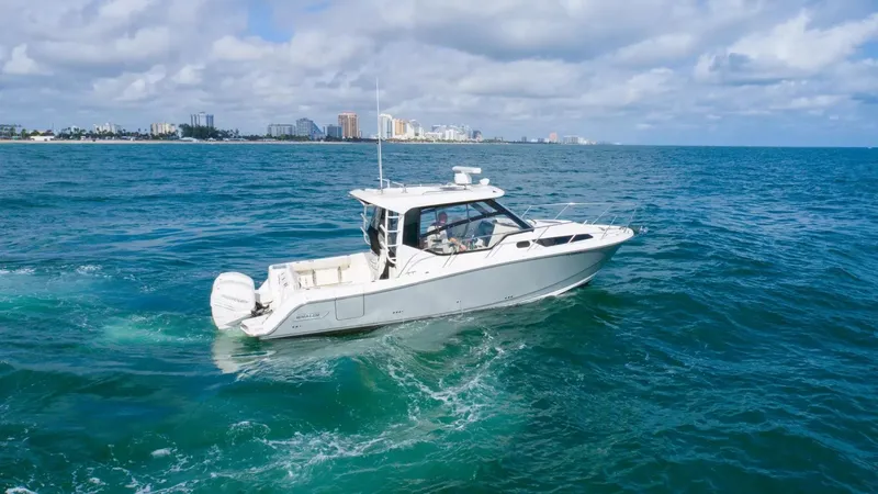  Yacht Photos Pics 2020 Boston Whaler 325 Conquest cruising on open ocean with city skyline in background.