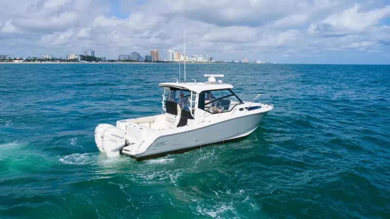  Yacht Photos Pics 2020 Boston Whaler 325 Conquest cruising on open ocean with city skyline in background.