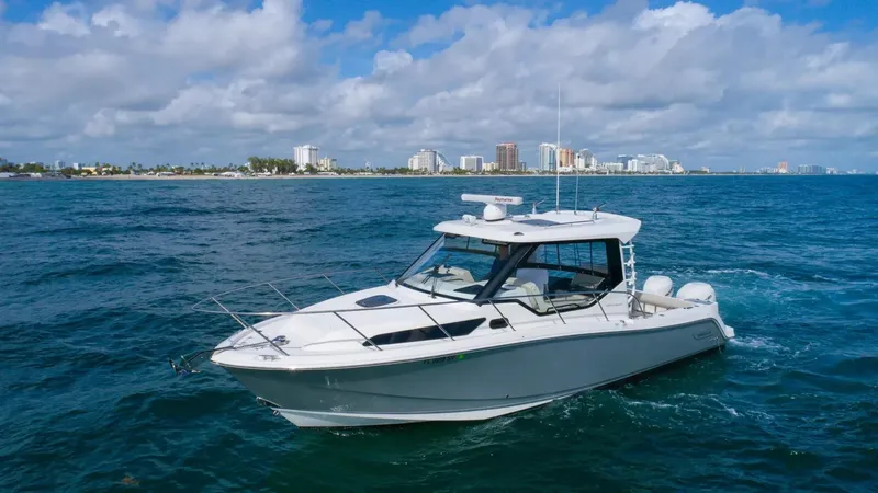  Yacht Photos Pics 2020 Boston Whaler 325 Conquest boat cruising on ocean with city skyline in background.
