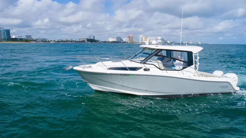  Yacht Photos Pics 2020 Boston Whaler 325 Conquest cruising on ocean near city skyline.