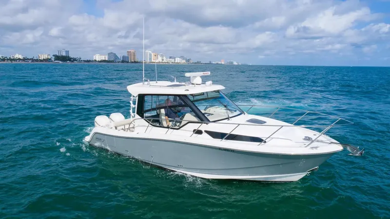  Yacht Photos Pics 2020 Boston Whaler 325 Conquest cruising on open ocean with city skyline in background.
