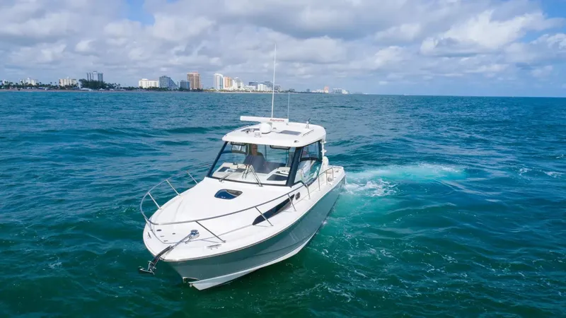  Yacht Photos Pics 2020 Boston Whaler 325 Conquest cruising on open ocean with city skyline in background.