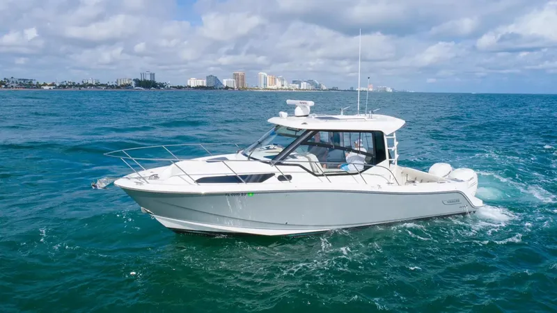  Yacht Photos Pics 2020 Boston Whaler 325 Conquest cruising on open ocean with city skyline in background.